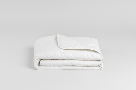 Gefaltete Kinder-Zirbendecke (100x140 cm) aus weißem, gestepptem Stoff vor einem cleanen, hellgrauen Hintergrund.