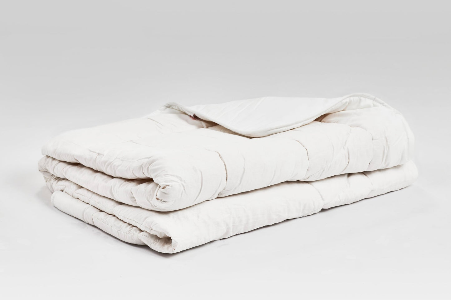 Handgenähte Zirbendecke mit Füllung aus Tencel und österreichischen Zirbenflocken, Bezug aus Baumwoll-Feinsatin, präsentiert auf weißem Hintergrund.